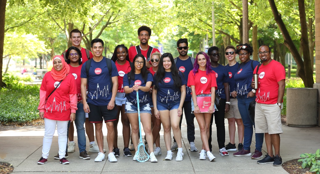 A diverse group of UIC students, all wearing UIC t-shirts, pose for a group photo on UIC's campus.