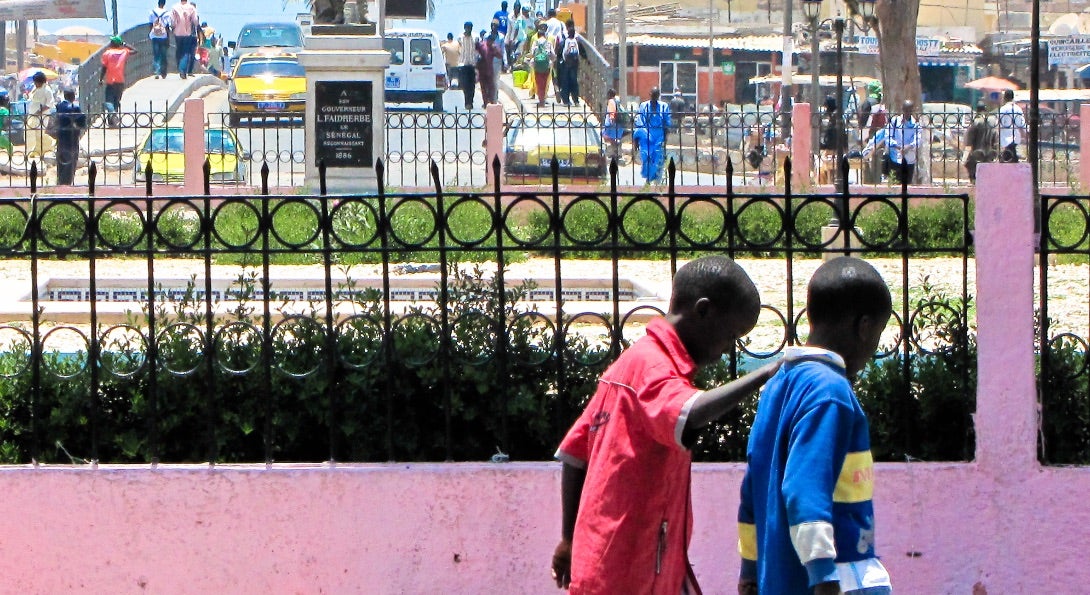 Two boys walk together down a street in Senegal.