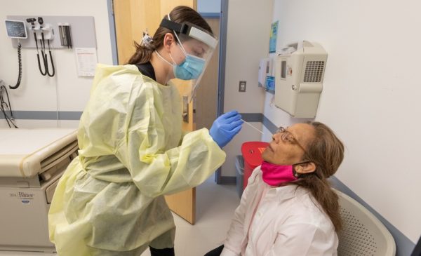 A healthcare professional inserts a nasal swab into the nose of a COVID-19 patient.