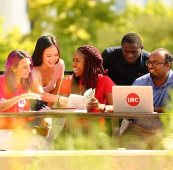 UIC students study together while sitting outdoors on campus.
                  