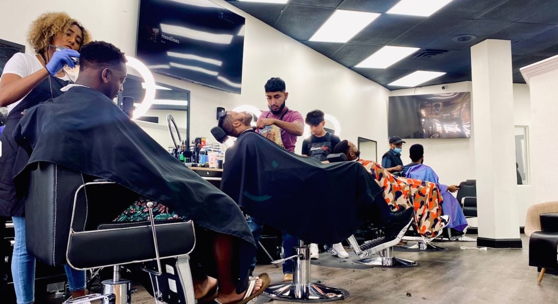 A barbershop, with numerous stylists working on the hair of customers.