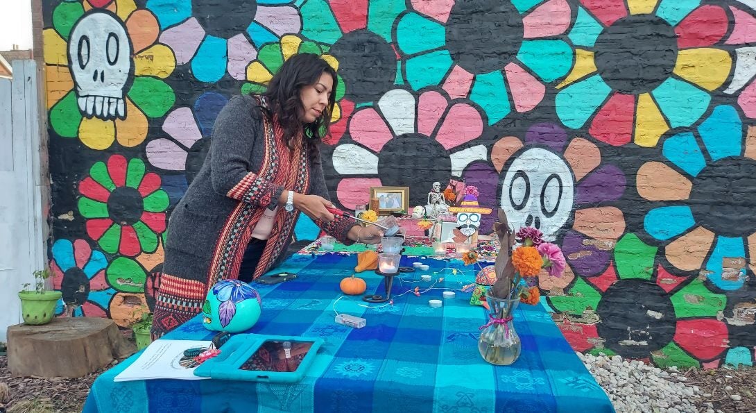 A woman lights a candle at a Day of the Dead celebration honoring workers that died during the COVID-19 pandemic.