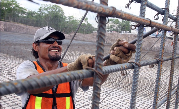 A construction worker uses a tool to modify a metal fence.