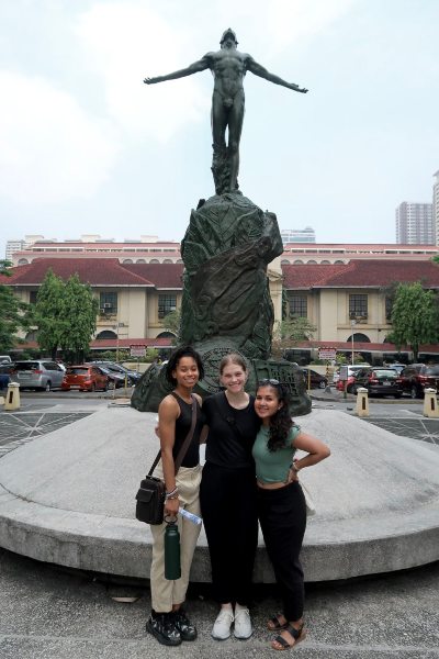 Thea and colleagues smiling in front of a statue.