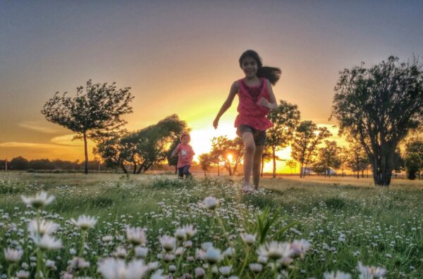 Children run in a park at sunset.