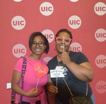 A woman and young girl pose at UIC School of Public Health Photo Booth
                  