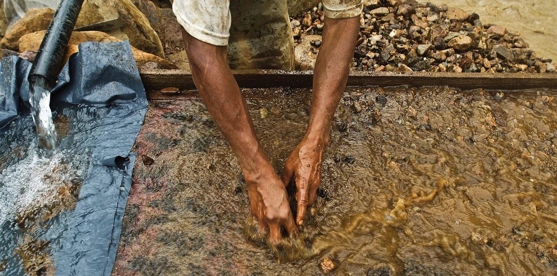 An artisanal gold miner sifts through silt combined with mercury as part of a gold mining process.