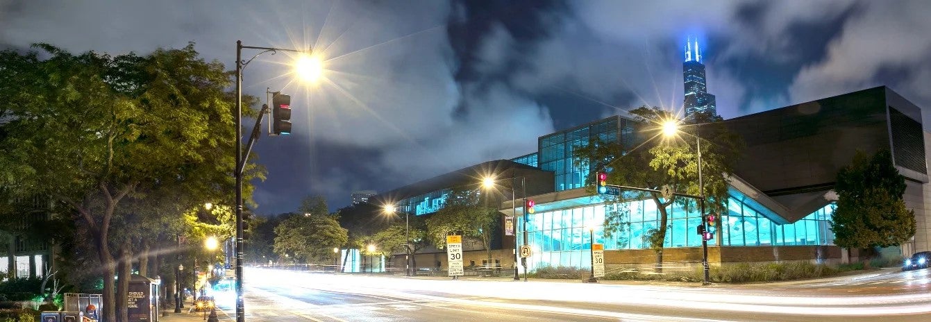 Cars travel down Hasted street at night past UIC's campus.