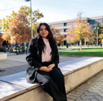 Monica Padilla sits on a stone bench at UIC's campus
                  