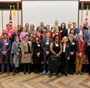 A group photo of all presenters from UIC's January SparkTalks in front of the presentation stage, with Chancellor Miranda.
                  