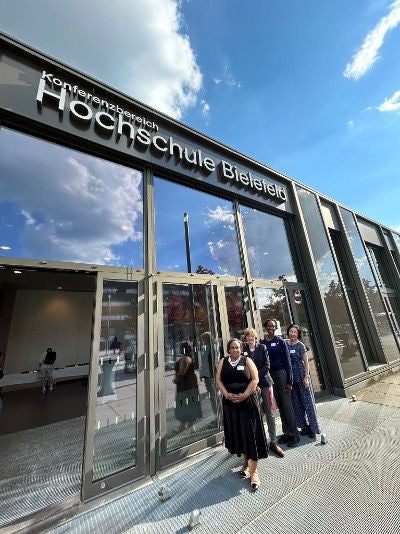 Three professors stand in front of Hochschule Bielefeld University of Applied Science