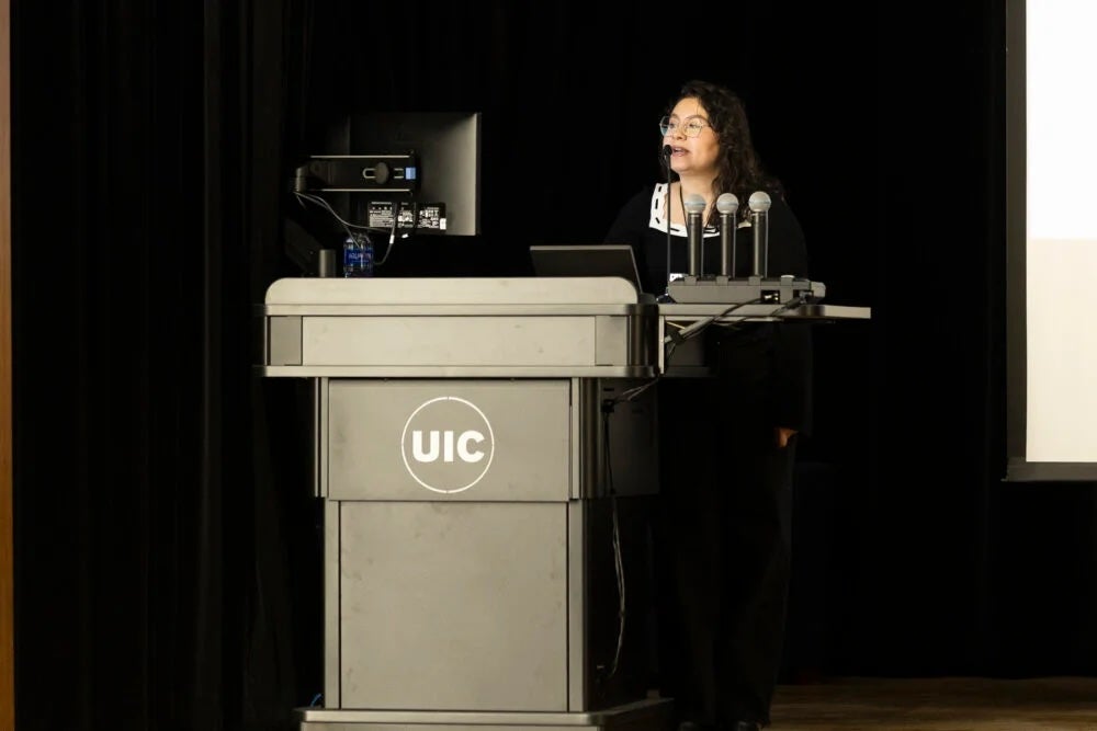 Lisa Beltran, conference chair, stands at a podium on a stage.