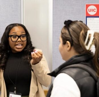 Naomi Samuels explains her research to a conference visitor in front of her research posterboard 